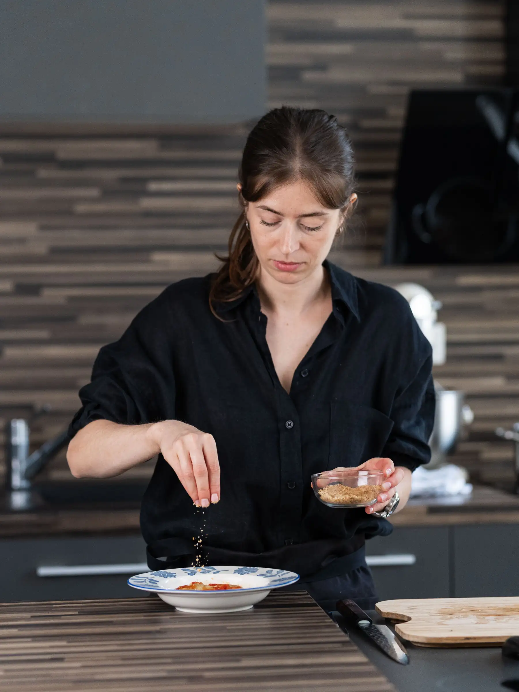 La cheffe à demeure dresse une assiette dans la cuisine
