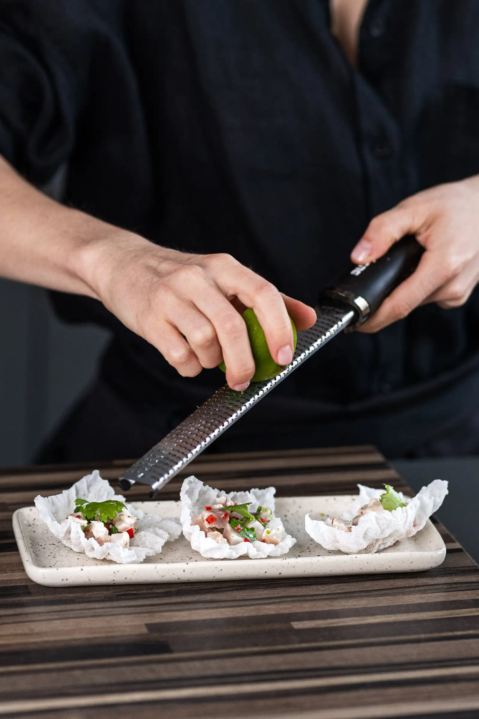 La cheffe râpe un agrume sur des bouchées pendant un cours de cuisine à domicile